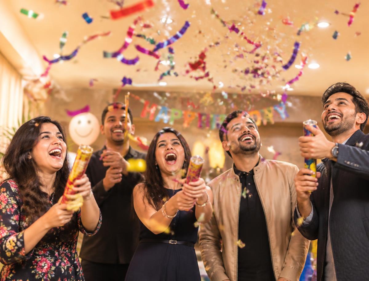 Friends bursting party poppers with colourful confetti at a birthday